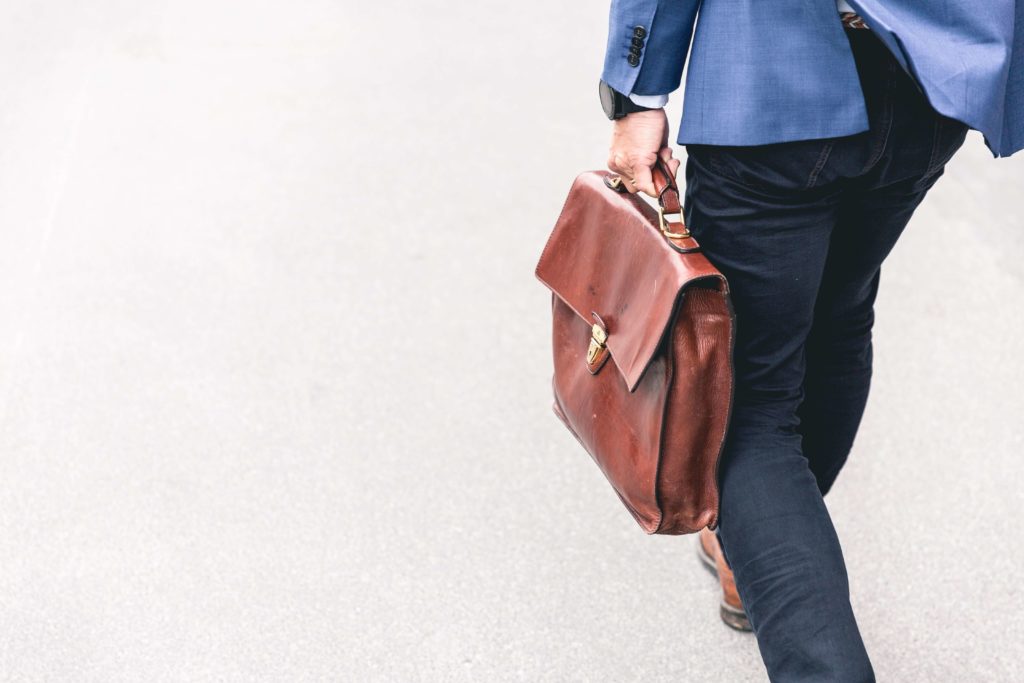 Someone walking while holding a leather bag